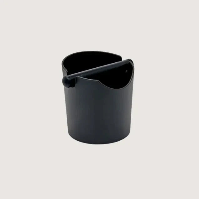 Black plastic coffee waste knock box container on a light gray background
