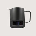 black espresso machine milk jug with built in thermometer showing temperature reading