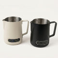 Two Thermosense milk jugs with built-in thermometer in beige and black. 