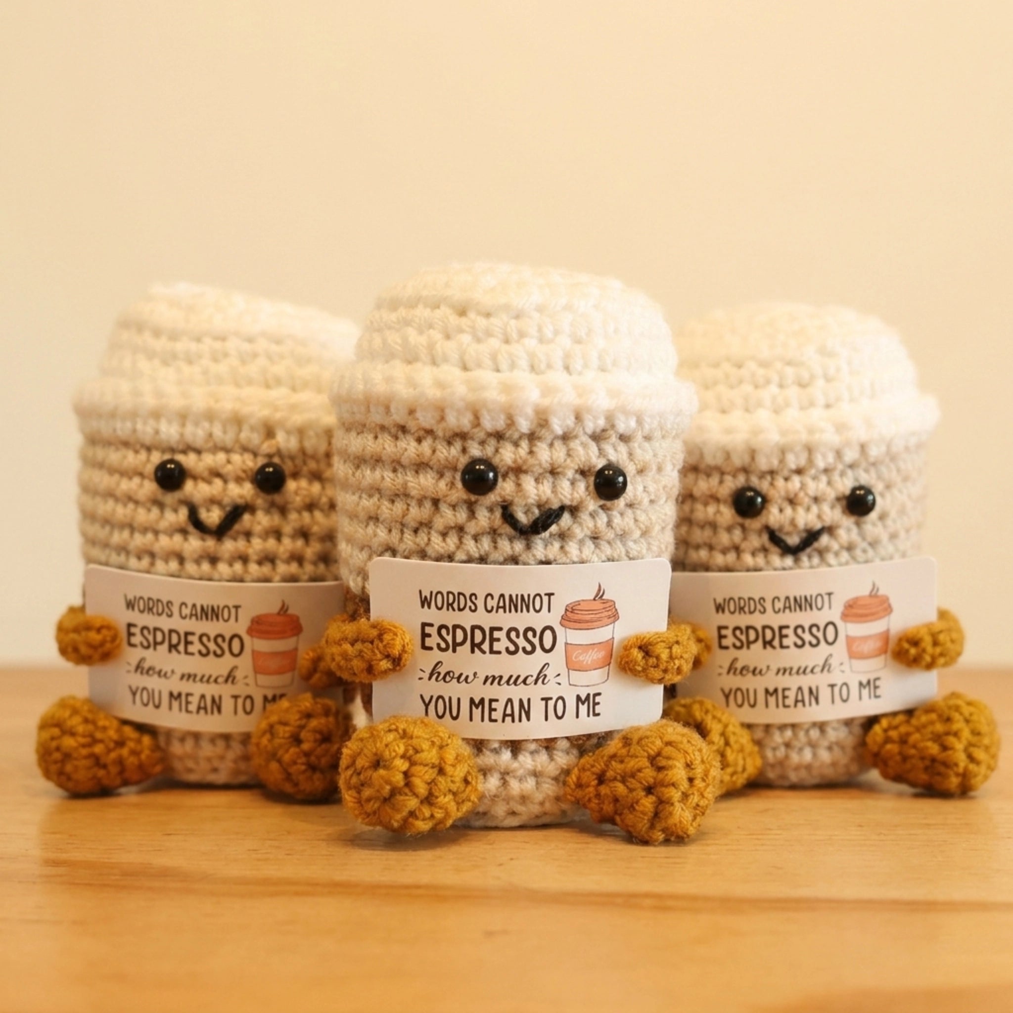 Three knitted coffee-themed characters with text on a wooden surface.