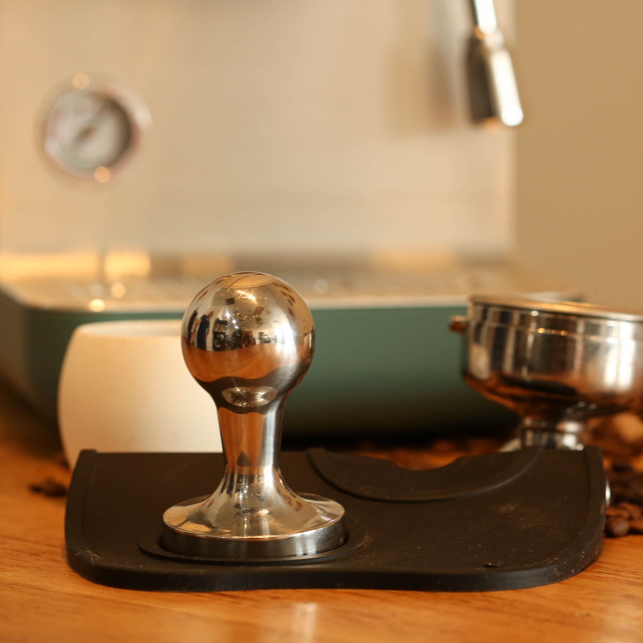 Coffee tamp on a wooden surface with a blurred kitchen background
